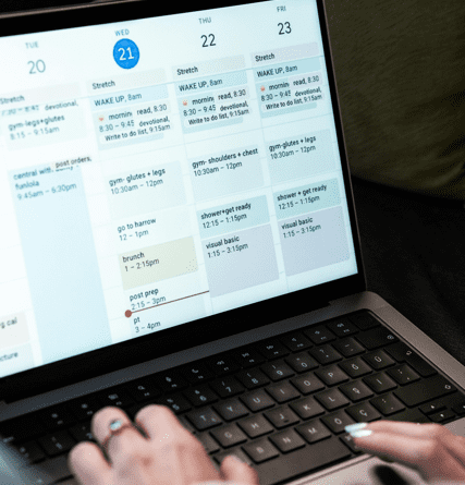 Una persona gestionando un calendario digital saturado de bloques de actividades en una laptop, representando el fenómeno del teatro de la productividad y la ineficiencia laboral.