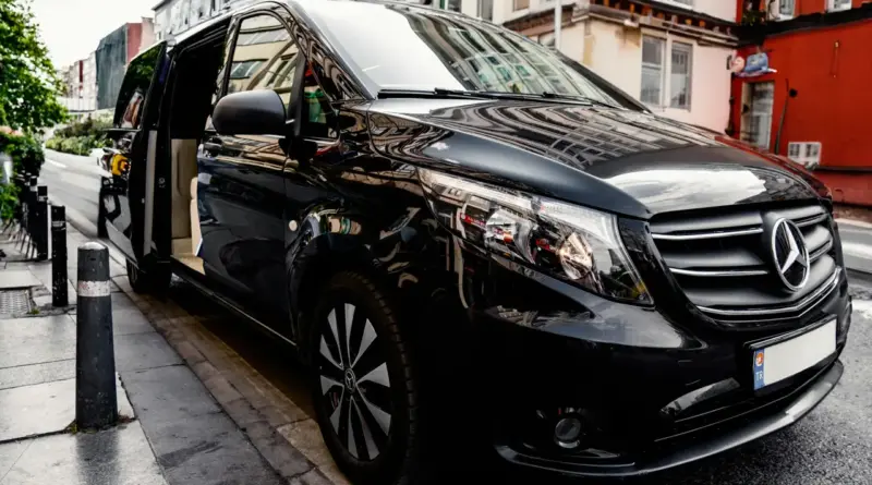 Camioneta Mercedes-Benz ejecutiva de color negro con la puerta abierta en entorno urbano, representando el servicio de logística terrestre y traslados premium.